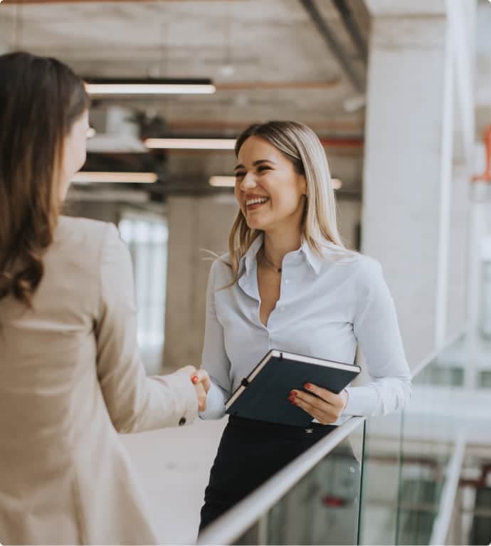 Two woman giving handshake and smiling at each other